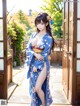 A woman in a blue kimono posing for a picture.