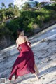 A woman in a red dress walking on the beach.