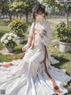 A woman in a white kimono sitting in the grass.