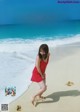 A woman in a red dress is walking on the beach.