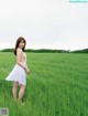 A woman in a white dress standing in a field of tall grass.