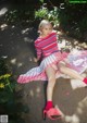 A woman in a pink and blue striped dress sitting on the ground.