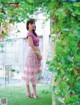 A woman in a pink dress standing in the grass.