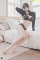 A woman in a black bra and panties sitting on a bed.