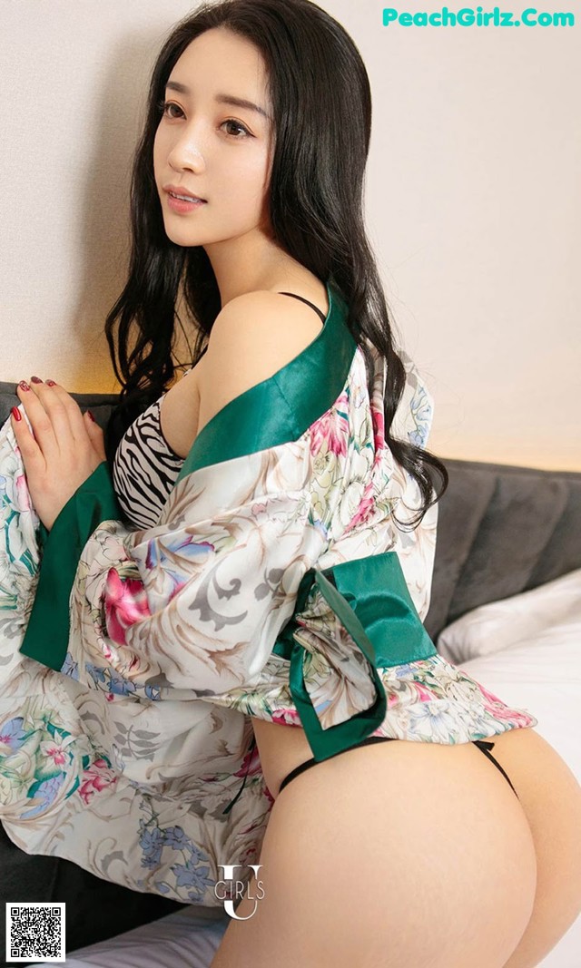 A woman in a green and white kimono sitting on a bed.