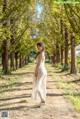 A woman in a white dress walking down a dirt road.