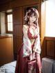 A woman in a red and white kimono standing in a room.