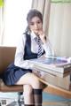 A woman sitting at a desk in a school uniform.