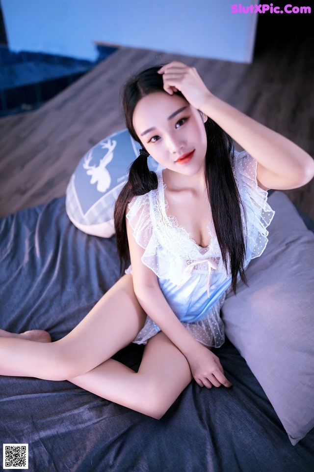 A woman sitting on top of a bed in a blue dress.