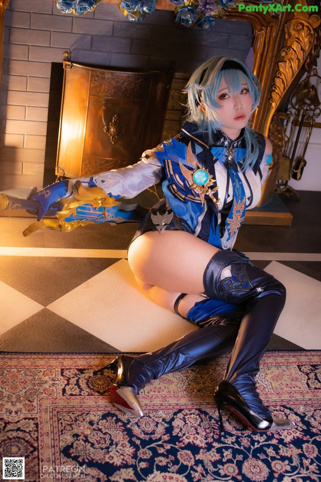 A woman in a blue and black outfit sitting on a rug.