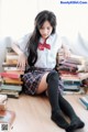 A woman sitting on the floor next to a pile of books.