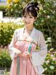 A woman in a pink and white hanbok posing for a picture.