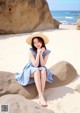 A woman sitting on a rock on the beach.