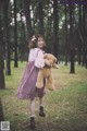 A woman in a red and white dress holding a teddy bear.