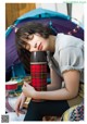 A woman sitting in front of a tent holding a thermos.