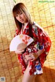 A woman in a red kimono holding a fan.