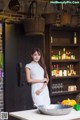 A woman in a white dress standing in front of a counter.