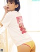 A woman in a white shirt and yellow panties posing for a picture.